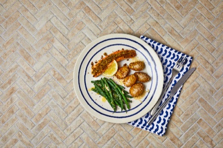 A dish of Pesto-Crusted Salmon With Cheesy Hasselback Potatoes