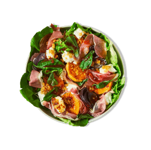 A colorful salad featuring prosciutto on a bed of mixed greens